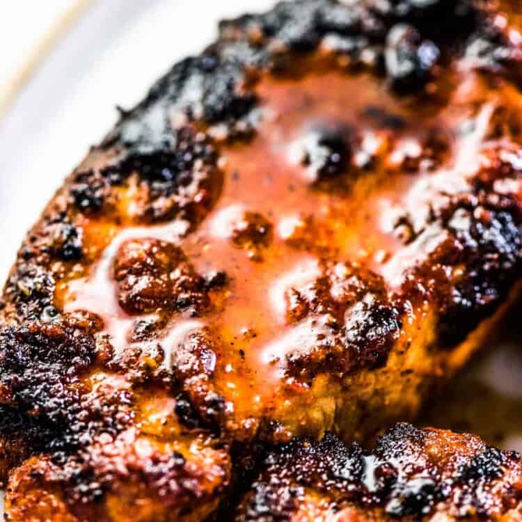 A close up of juicy grilled pork chops on a plate.