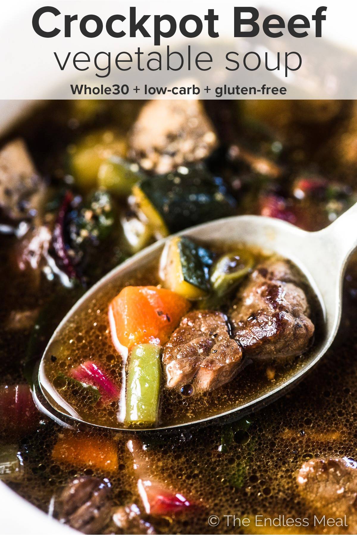 A close up of crockpot beef vegetable soup with the recipe title on top of the picture. 