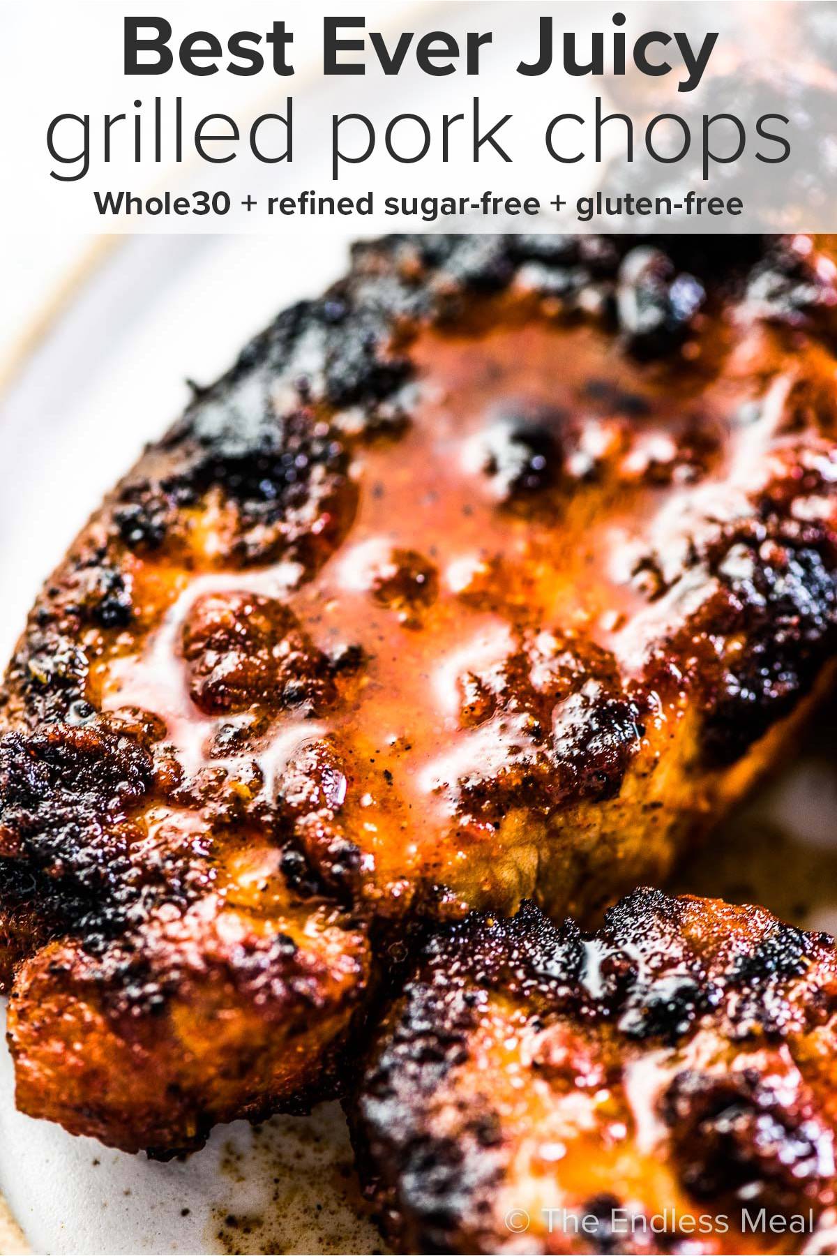 Juicy Grilled Pork Chops on a plate with the recipe title at the top of the picture.