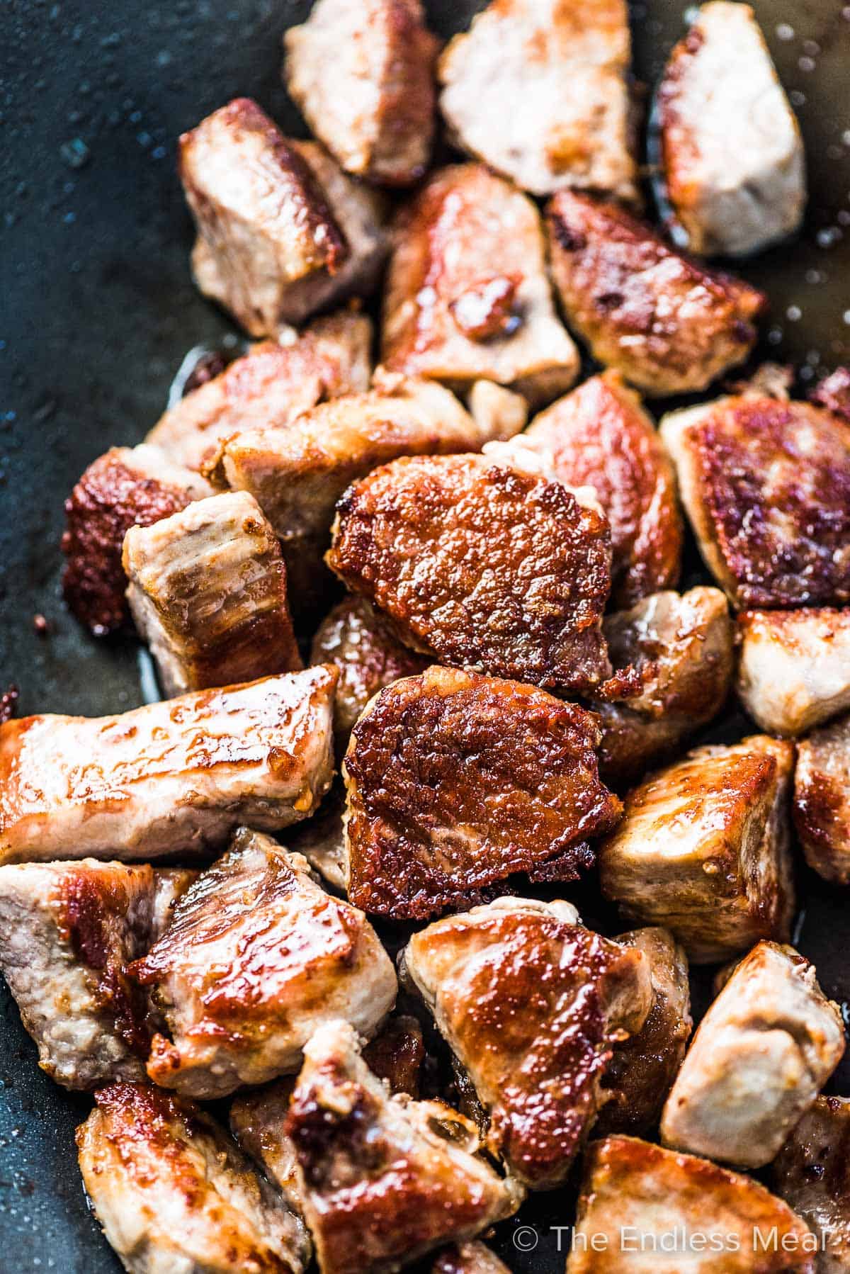 Browned pork loin chunks in a pan.