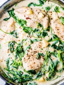 A pan of garlic chicken in a saucy dairy-free cream sauce with lots of spinach.