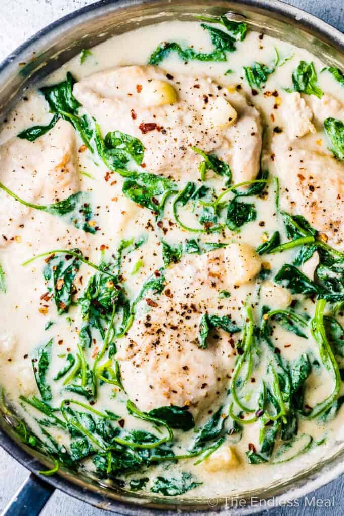A pan of garlic chicken in a saucy dairy-free cream sauce with lots of spinach.