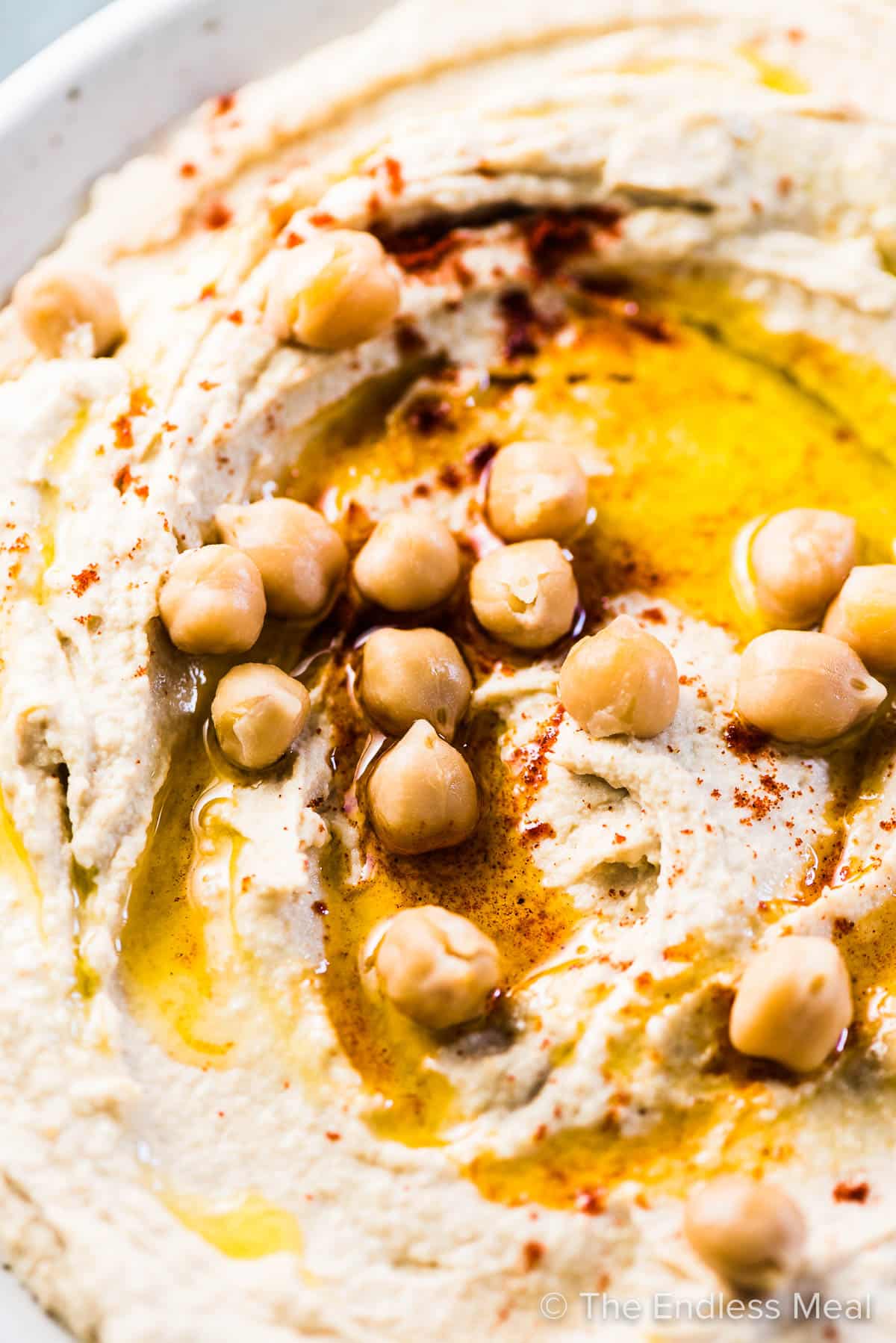 A close up shot of an easy hummus recipe with chickpeas and olive oil on top.