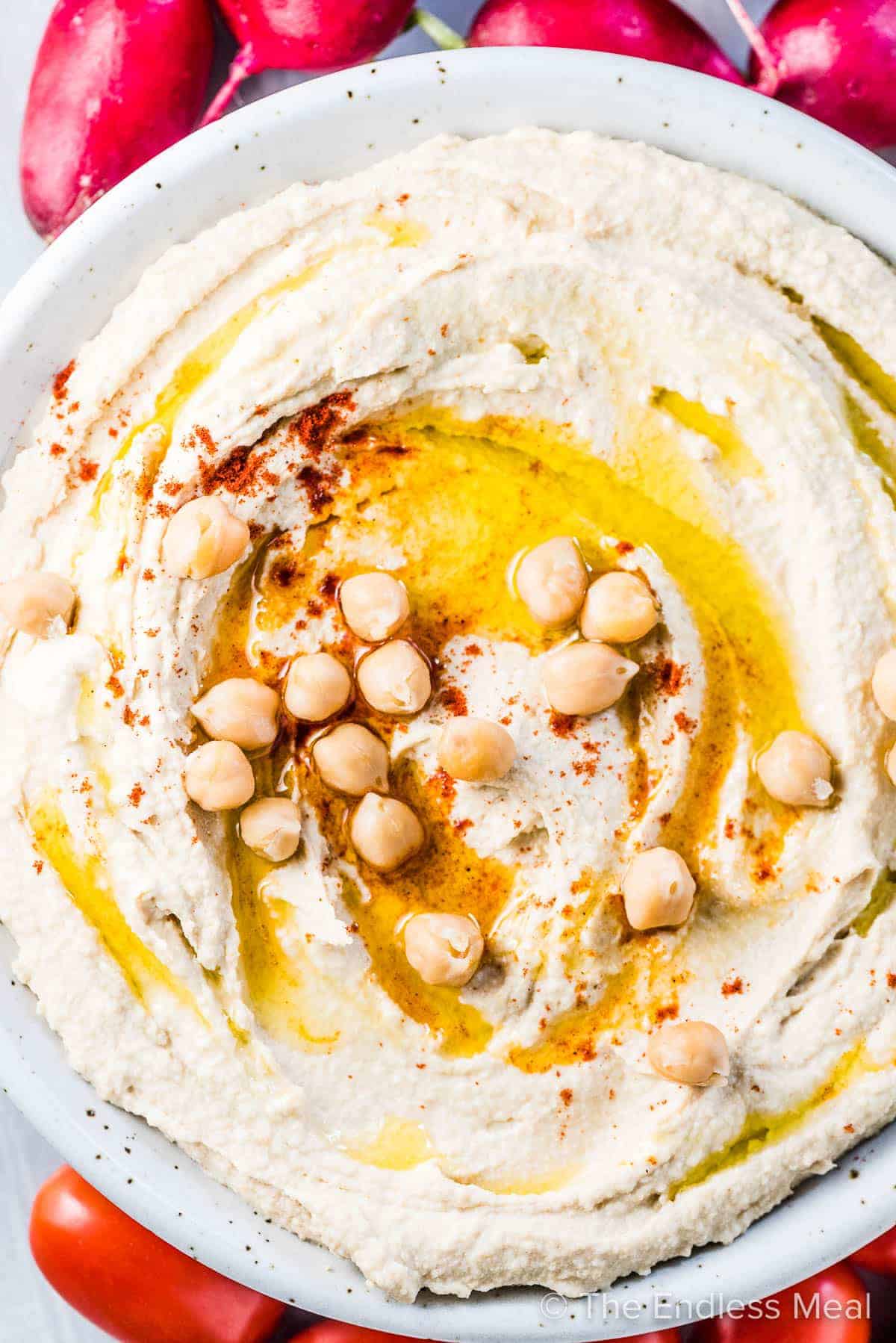 Looking down on a plate of this homemade hummus recipe that's garnished with chickpeas and olive oil.