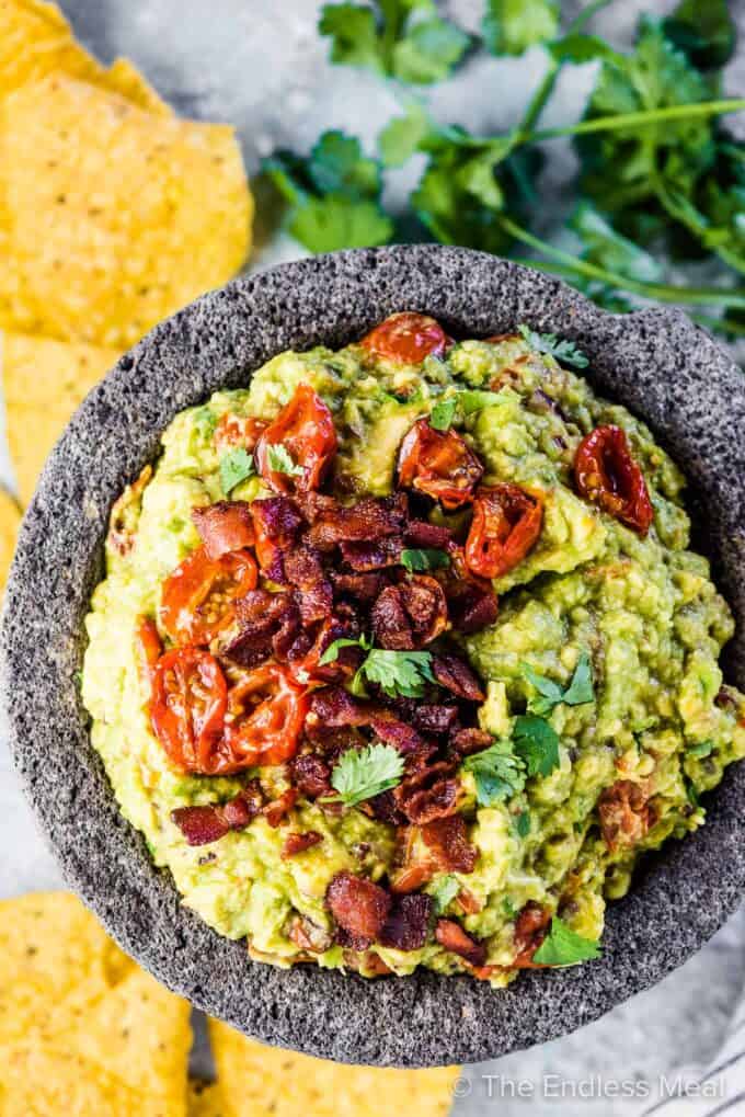 Bacon guacamole in a serving bowl with chips on the side.