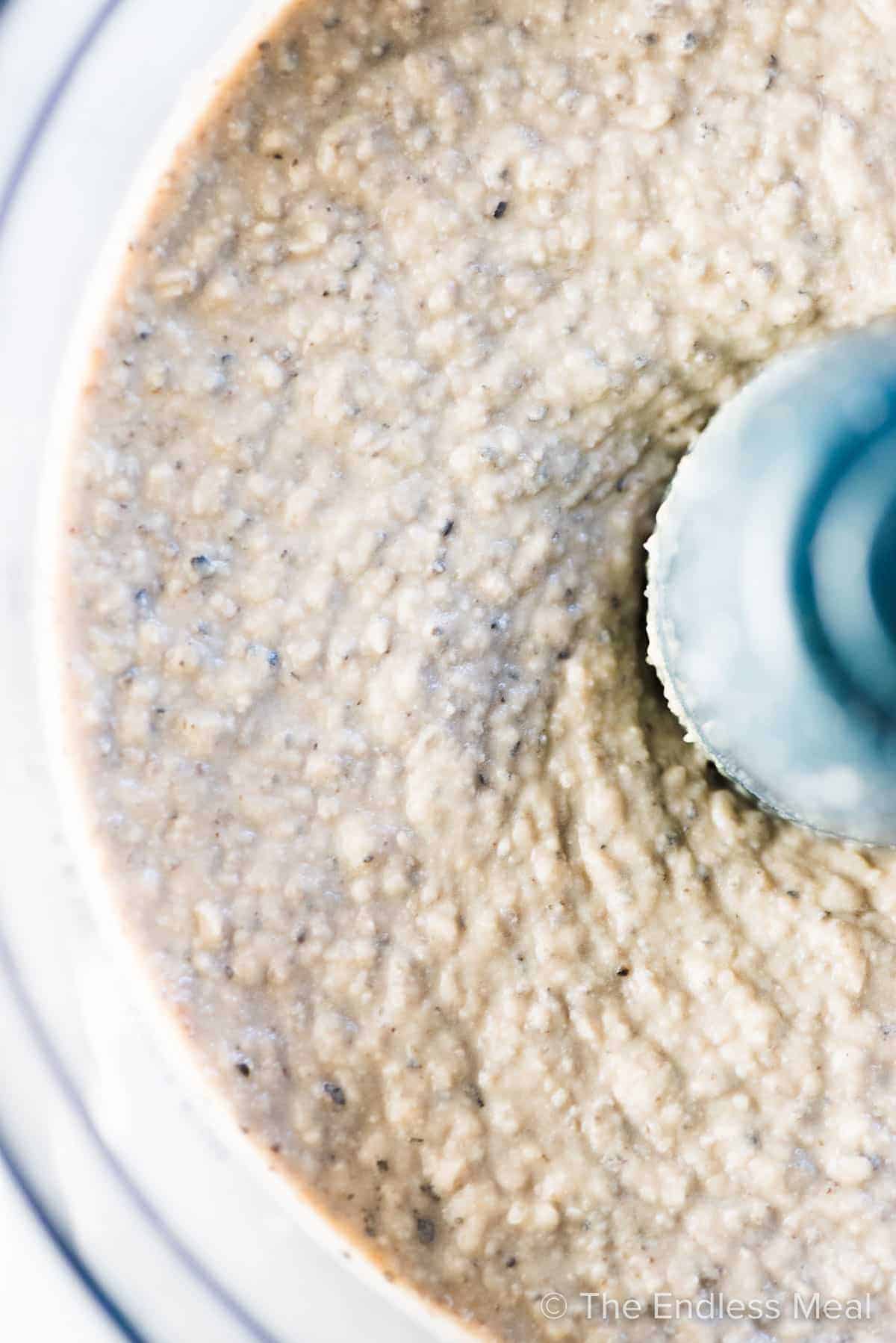 Creamy white bean dip with olives in a food processor.