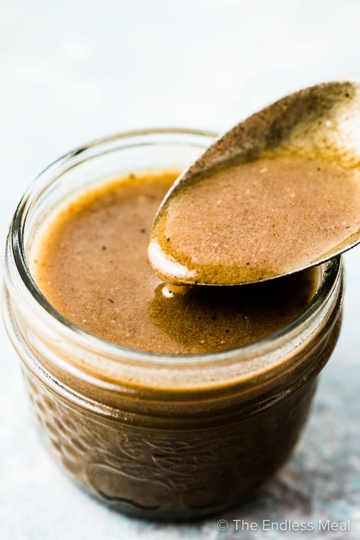 Brown butter vinaigrette in a small glass jar with a spoon.