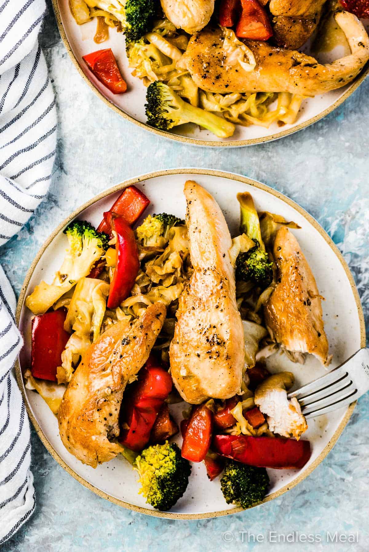 Chicken and cabbage stir fry on a plate with a fork taking a bite,