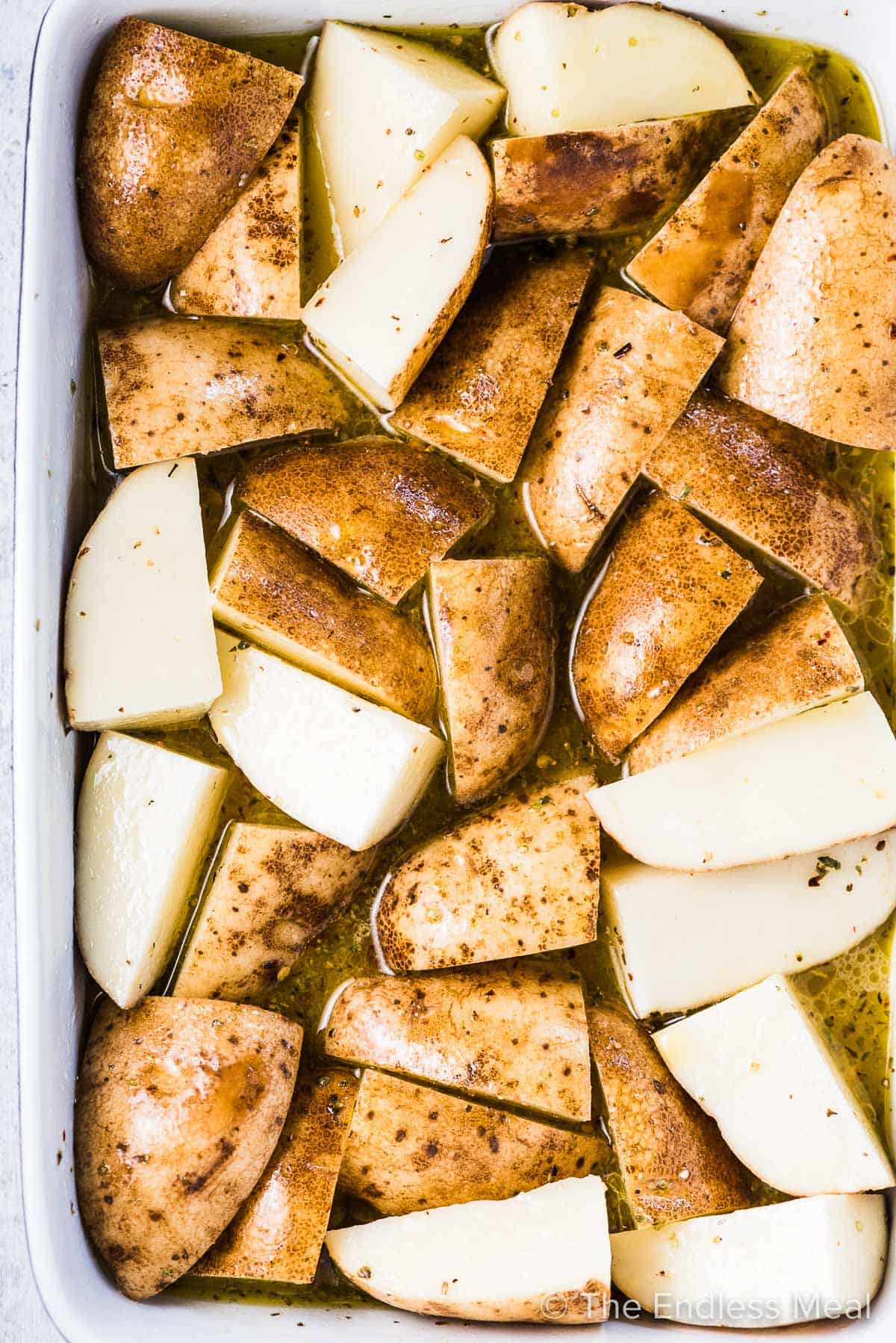 Lemon potatoes in a roasting pan before going into the oven.
