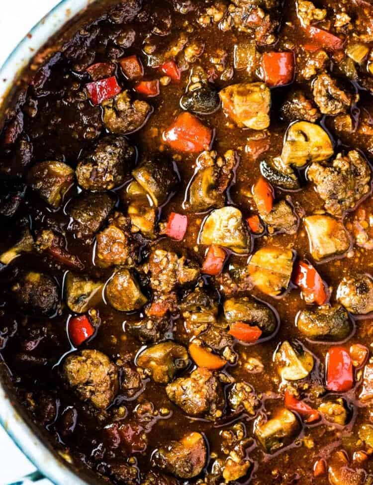 A big pot of sausage chili with lots of sausage chunks and mushrooms in it.