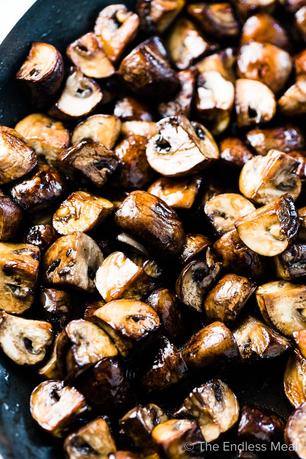 A pan filled with sauteed quartered mushrooms.