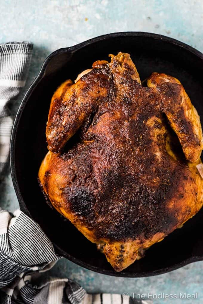Crockpot roast chicken in a black pan.