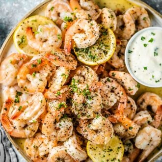 A plate of garlic butter baked shrimp with dip on the side.