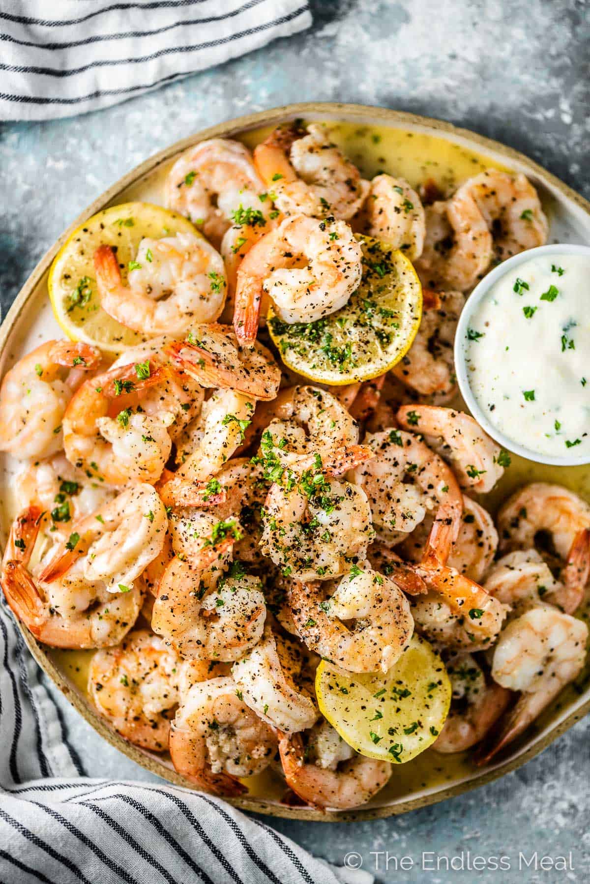 A plate of garlic butter baked shrimp with dip on the side for one of the best healthy appetizers for the holidays.