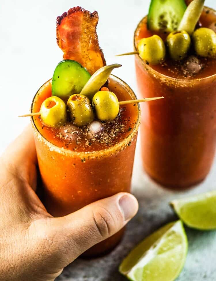 A hand grabbing a Caesar cocktail made with homemade Clamato.