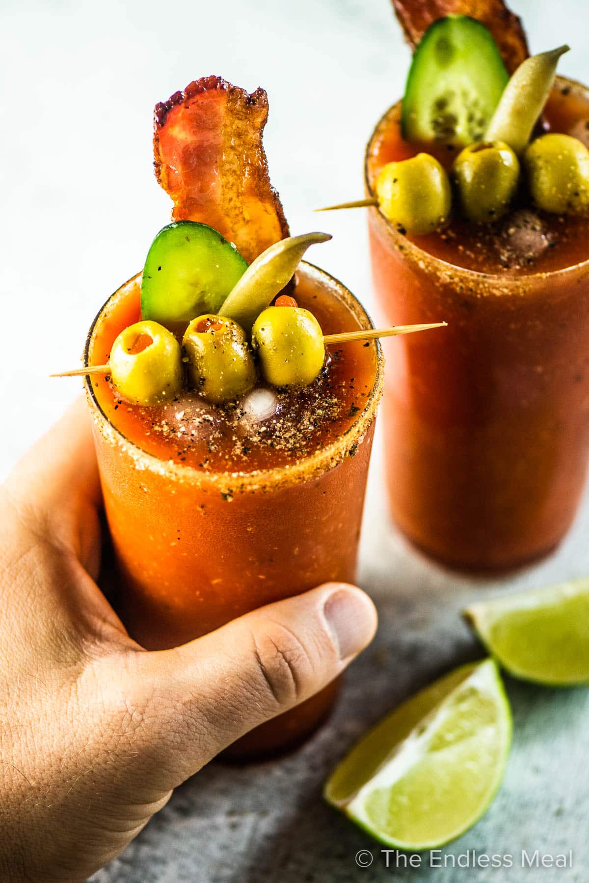 A hand grabbing a Caesar cocktail made with homemade Clamato.