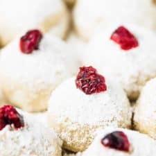 A closeup of snowball cookies topped with cranberries.