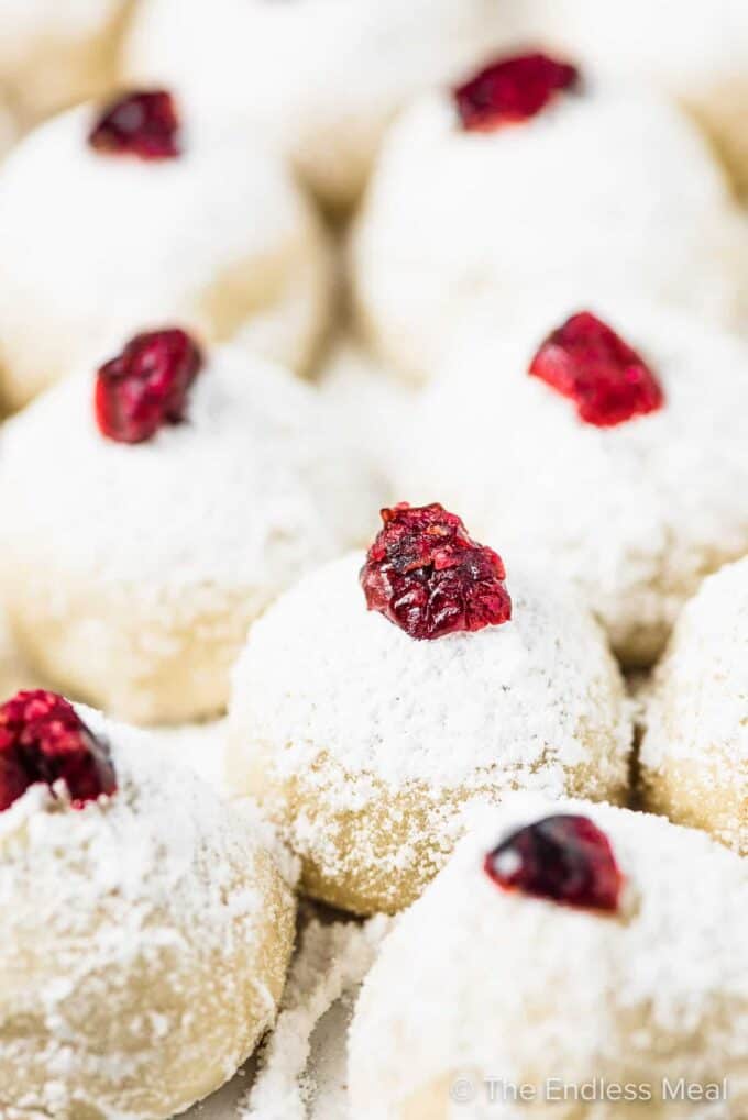 A closeup of snowball cookies topped with cranberries.