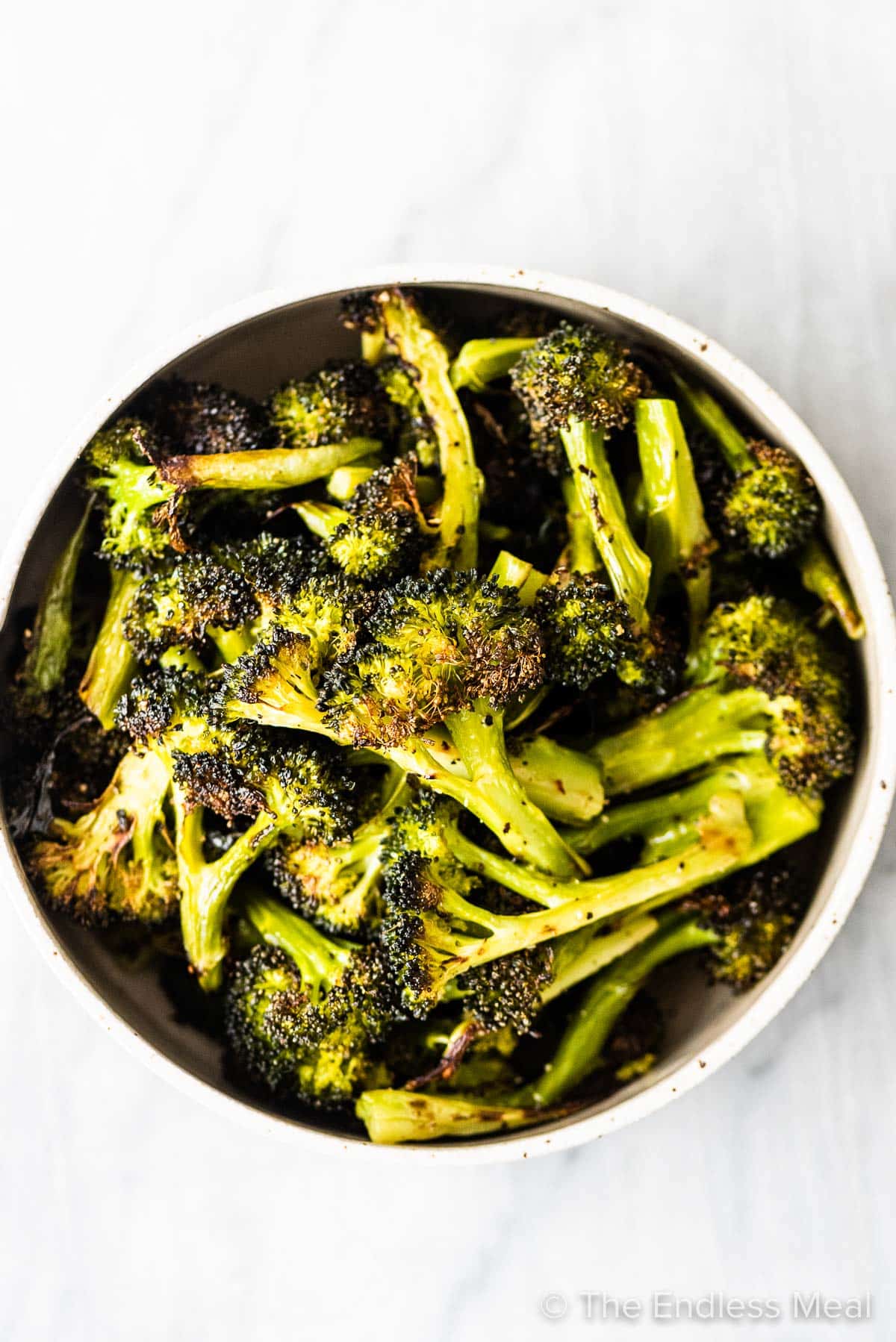 A serving bowl full of roasted broccoli