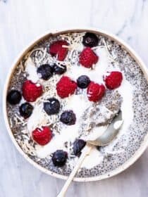 Chia pudding in a bowl on a marble background with berries on top.