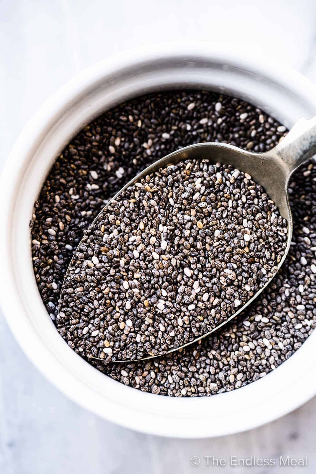 Black chia seeds in a white bowl.
