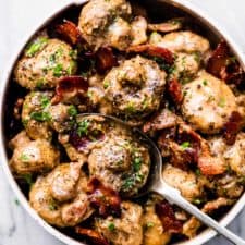 Creamy garlic mushrooms with bacon in a white bowl.