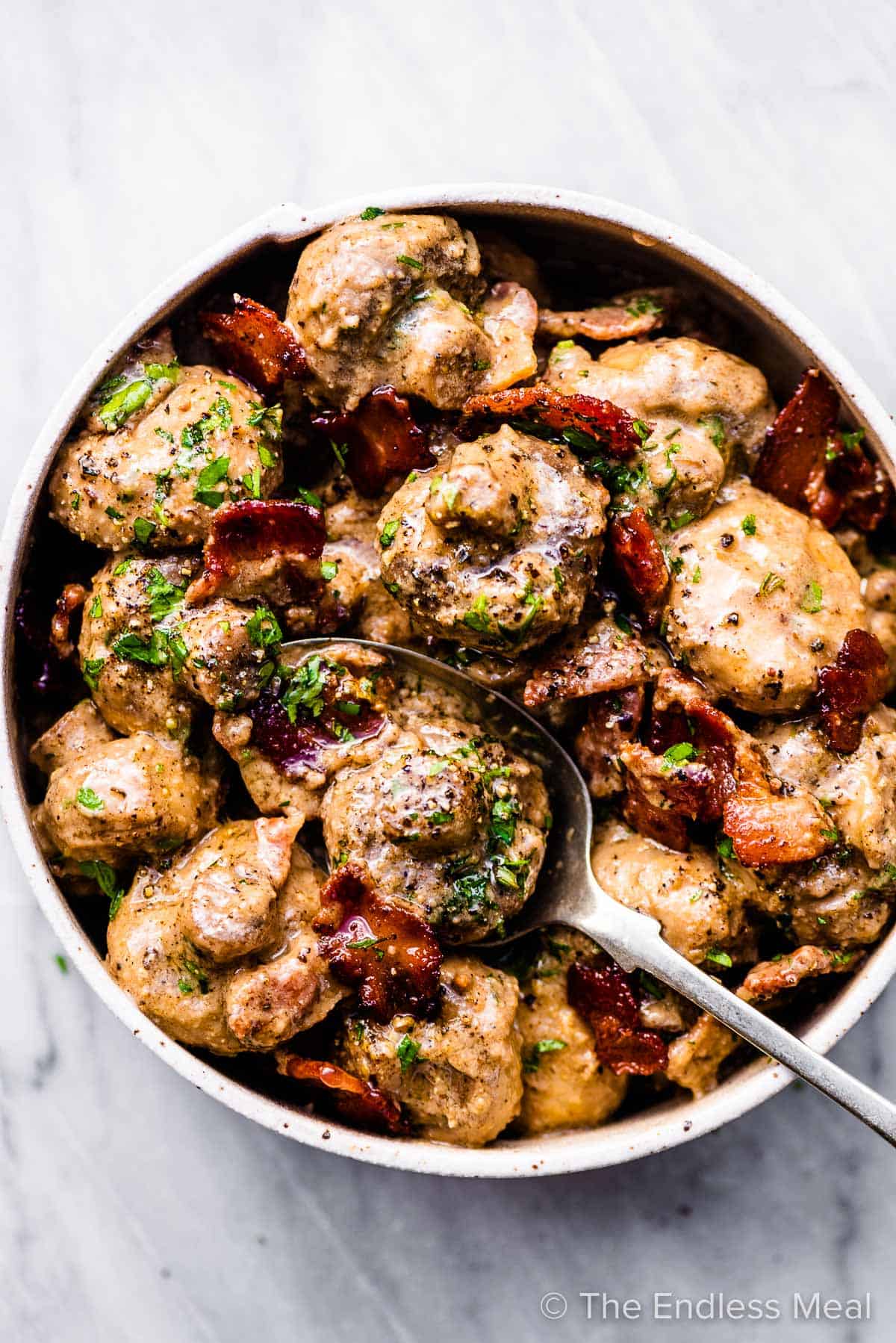 Creamy garlic mushrooms with bacon in a white bowl.