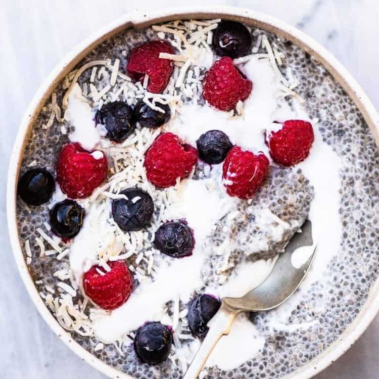 white bowl with chia seed pudding, topped with coconut, milk, and berries
