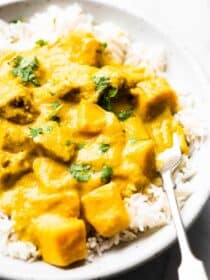 Mango chicken curry in a bowl with rice and a fork.