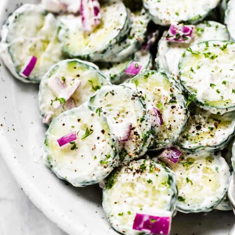 A close up of this creamy cucumber salad in a white serving bowl.