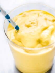 Mango smoothie in a glass with a straw.