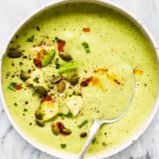 A bowl of avocado soup with a spoon inside.