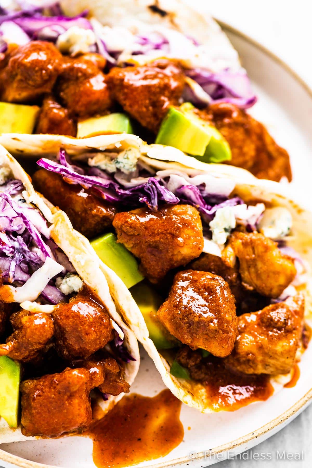Buffalo chicken tacos on a white plate. 