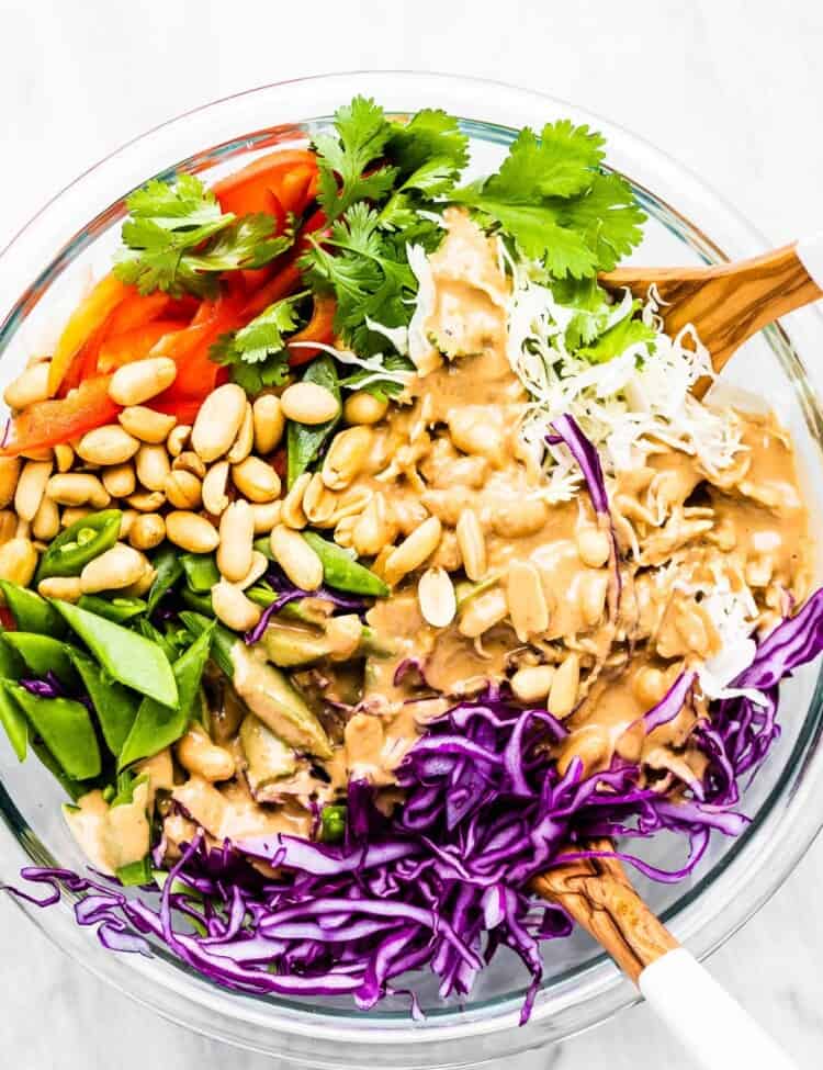 Peanut dressing poured over top of salad in a bowl.