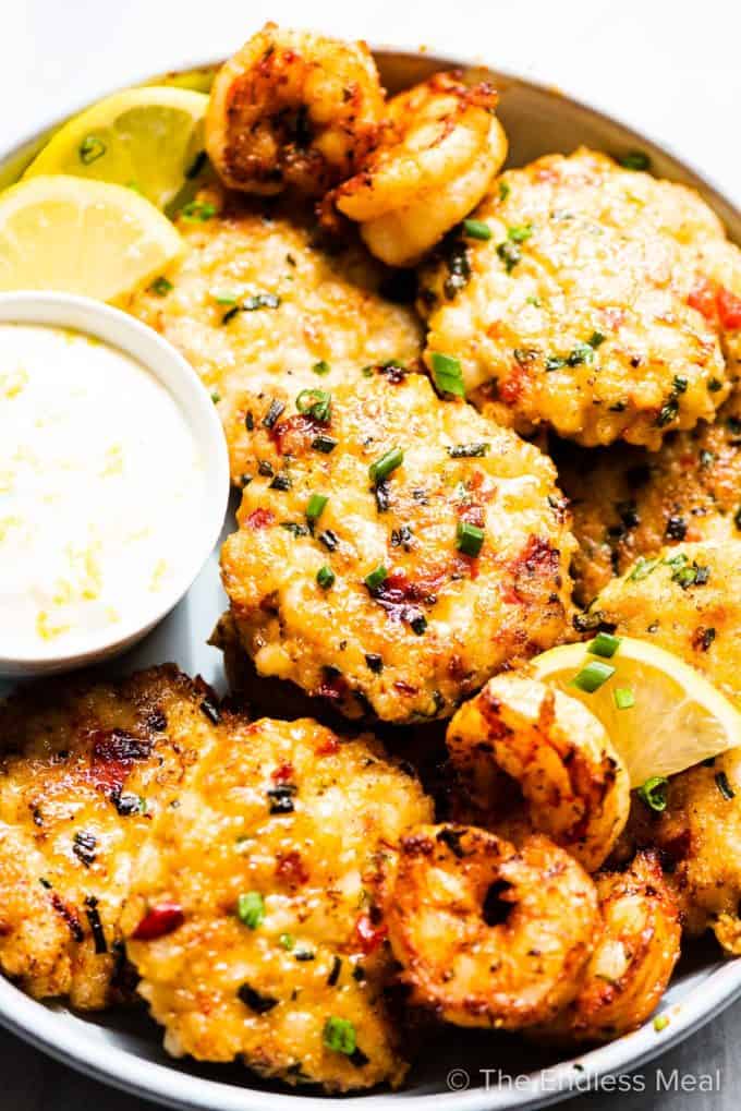 Shrimp cakes and cooked shrimp on a plate with lemons and aioli.