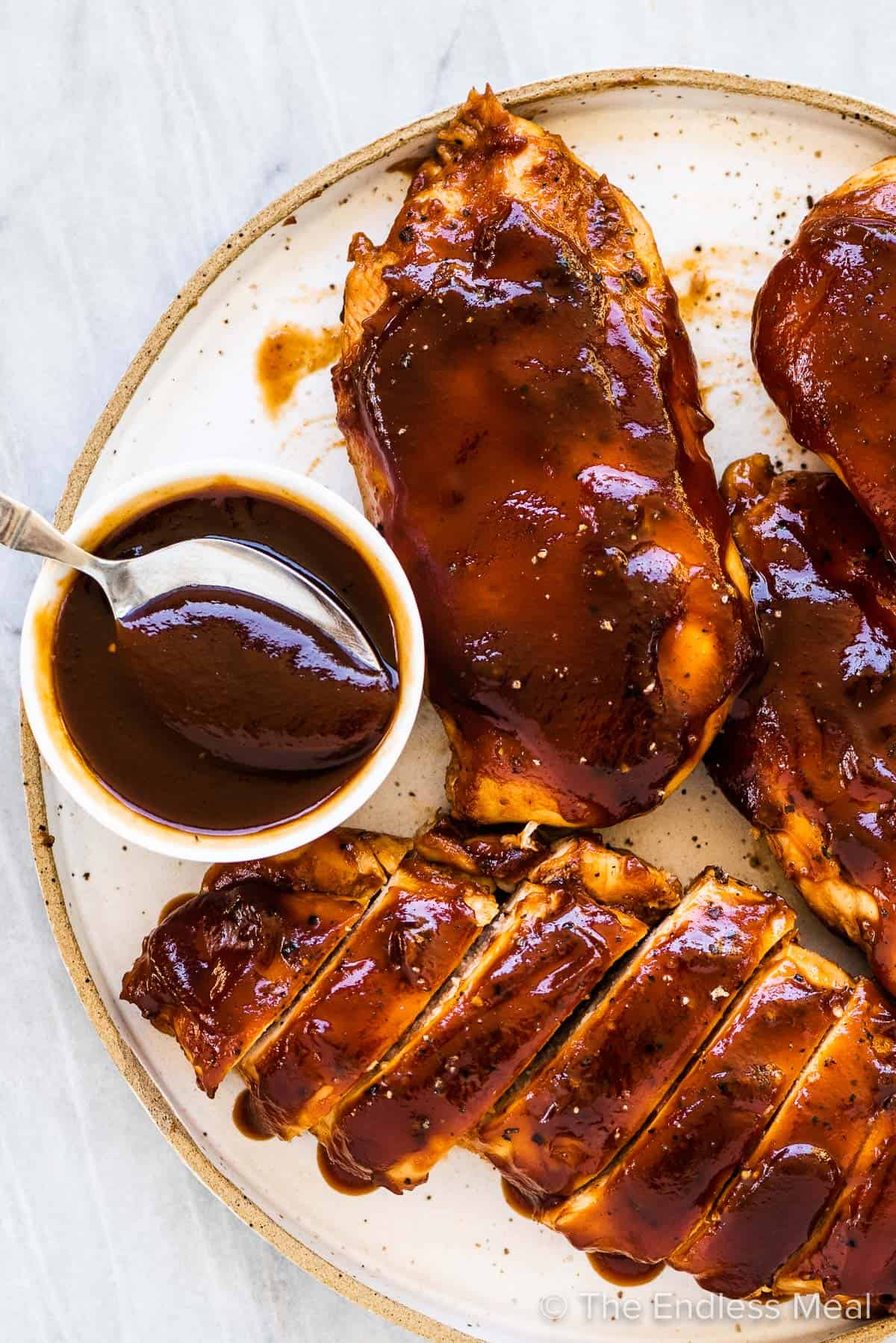 BBQ chicken on a plate with a side of homemade bbq sauce. 