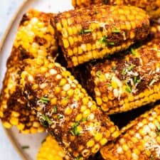 Cheesy corn on the cob piled high on a plate.