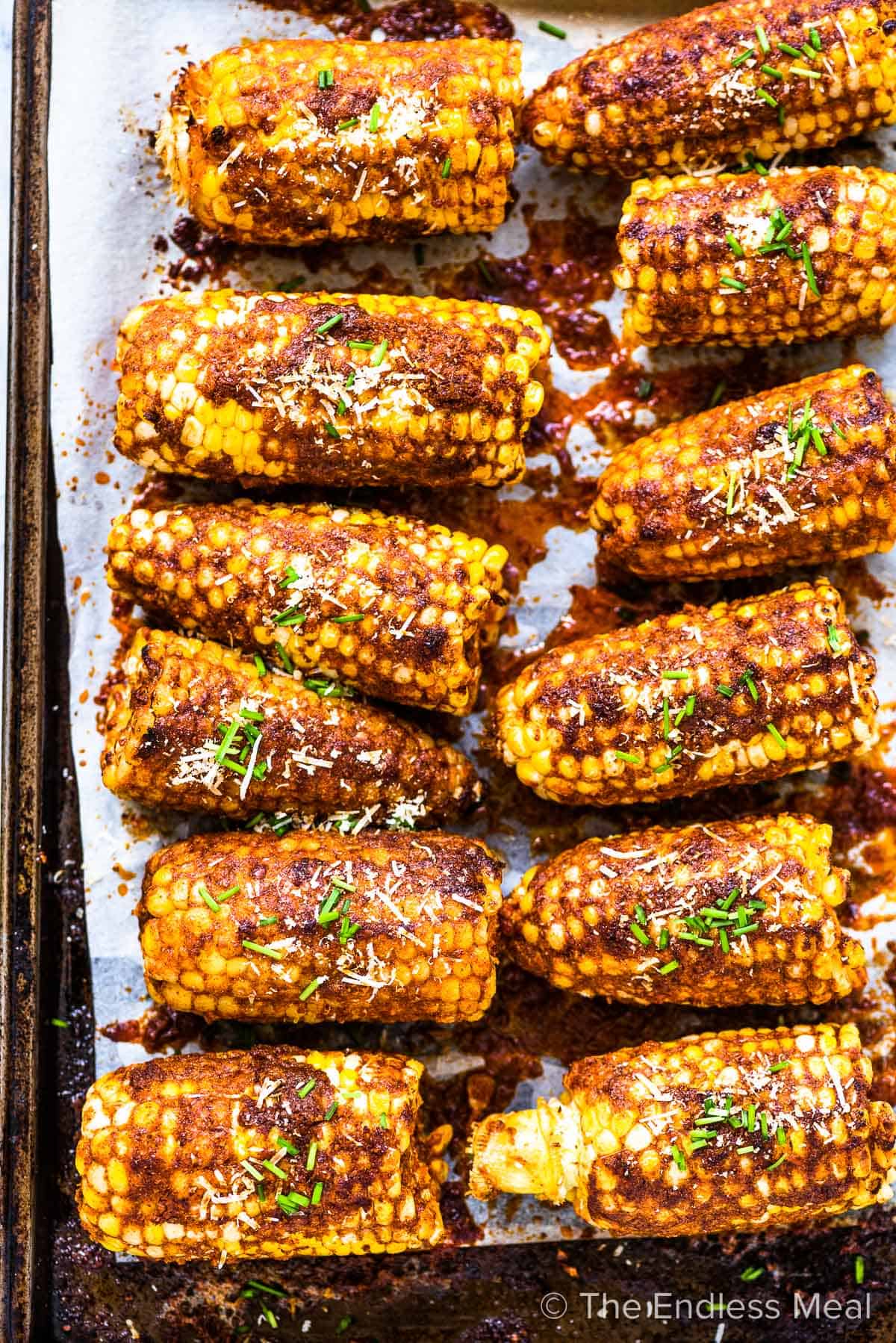 Looking down on a sheet pan of baked parmesan corn on the cob.