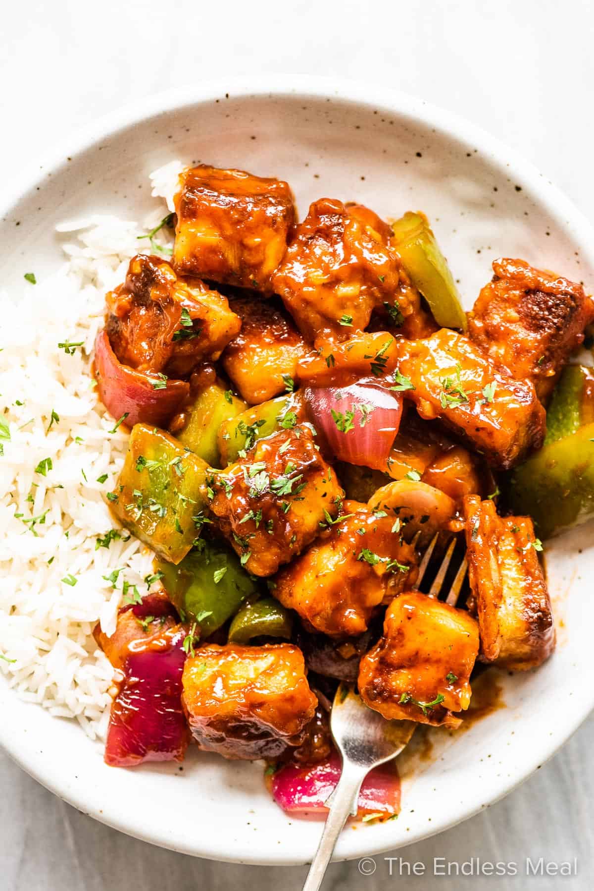 Sweet chili paneer on a white plate with rice. 
