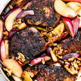 A pan of pork chops with apples and onions.
