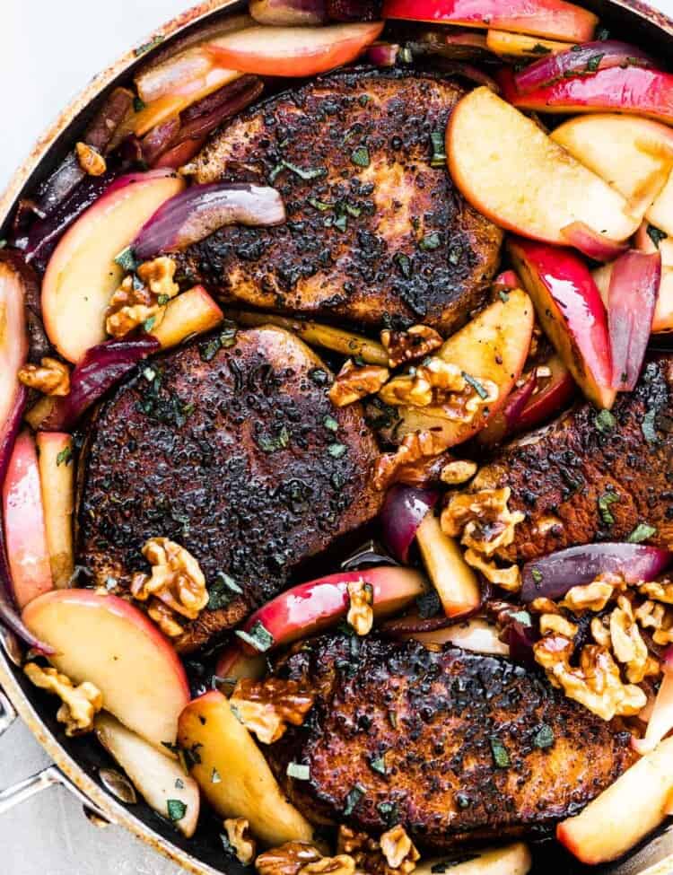 A pan of pork chops with apples and onions.