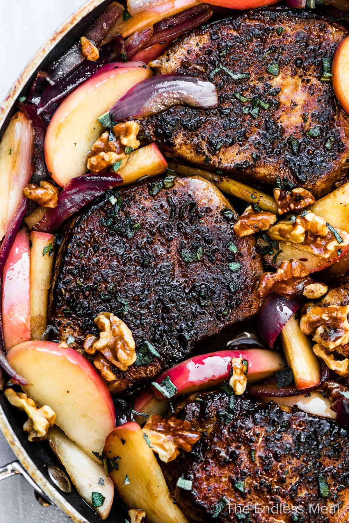 Pork chops with apples and onions in a pan.