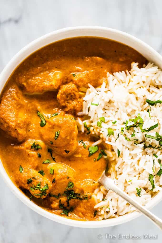 Slow cooker butter chicken in a bowl with rice.