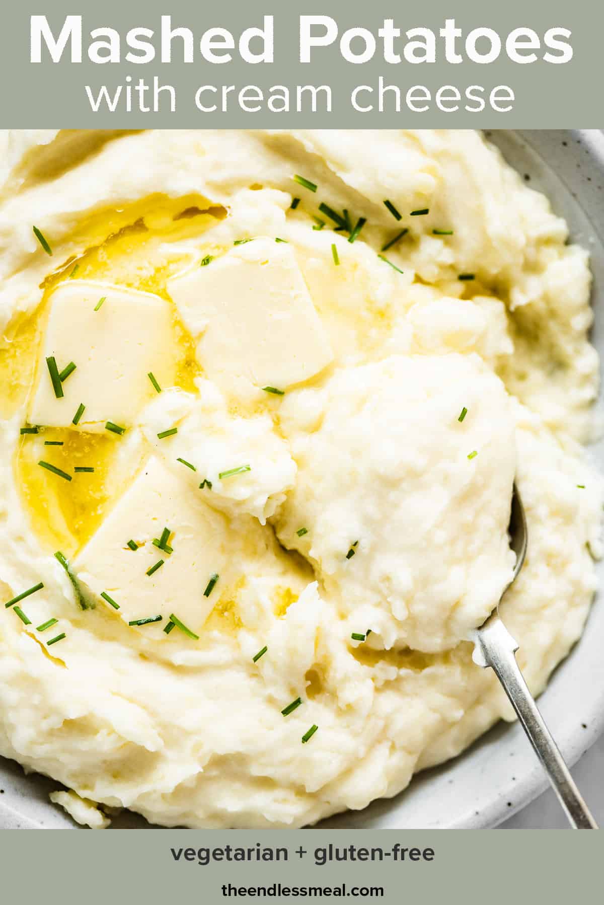 Cream cheese mashed potatoes in a white serving bowl with butter and chives and the recipe title on top of the picture.