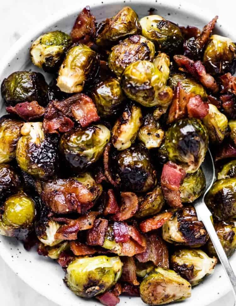A serving bowl filled with roasted brussels sprouts with bacon.