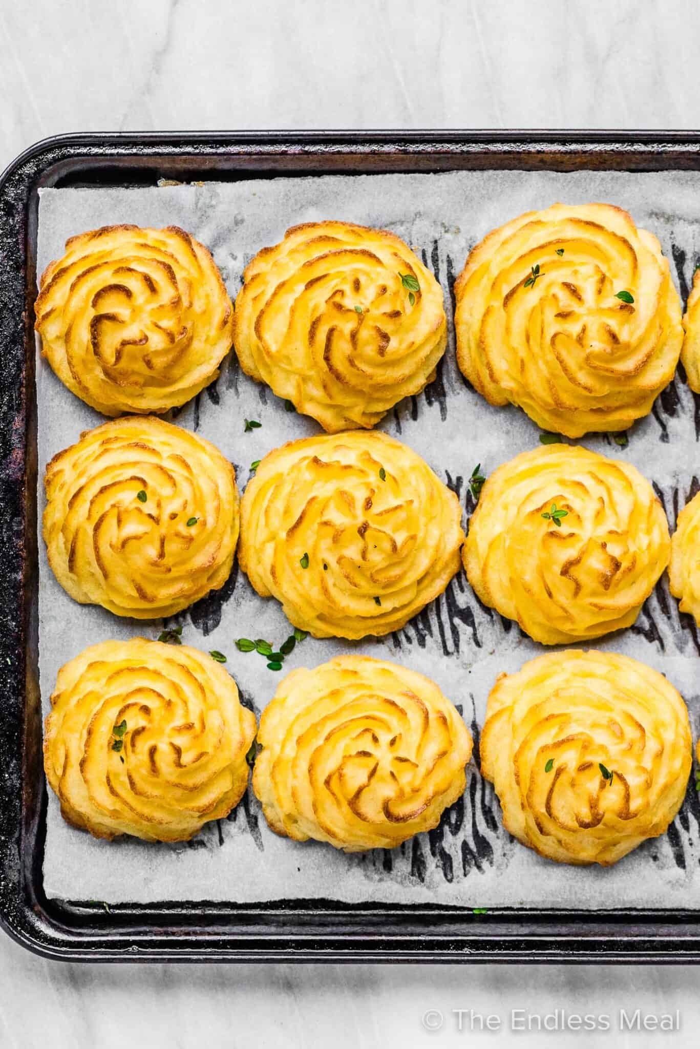 9 duchess potatoes lined up on a baking sheet.