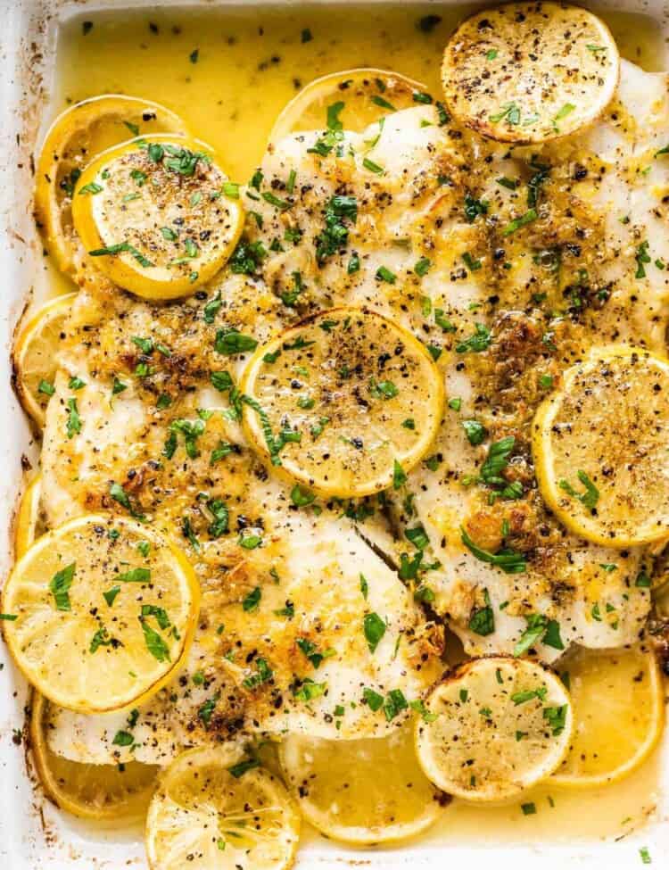 Baked Fish with Lemon Garlic Butter in a white baking dish with parsley on the top.
