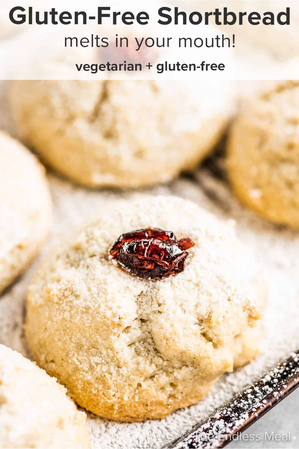 A closeup of gluten free shortbread cookies with dried cranberries on top on a baking sheet with the recipe title on top of the picture.