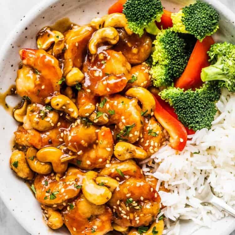 Cashew shrimp in a white bowl with broccoli and rice.