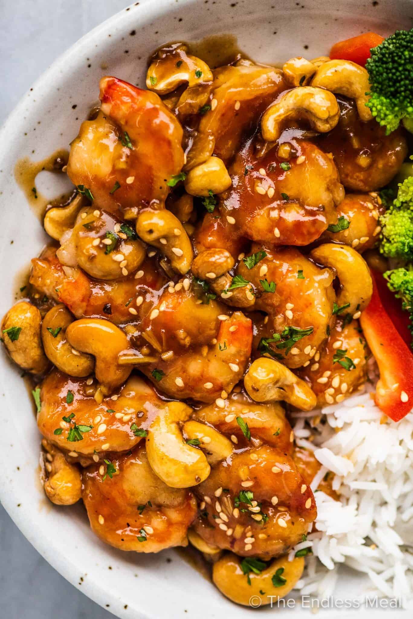 A close up of a bowl full of cashew shrimp with some rice.